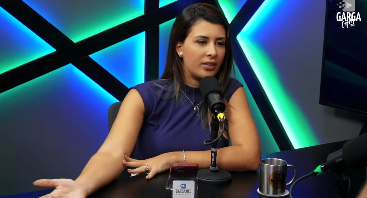 Convidada à mesa com painel de LED ao fundo, em gravação transmitida ao vivo